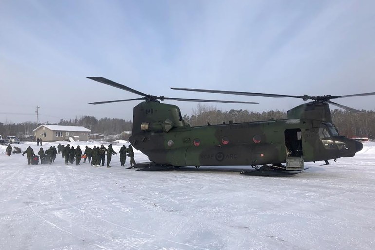 Members of the Royal Canadian Air Force unload a Chinook helicopter full of COVID relief supplies