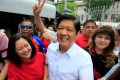 Bongbong Marcos in a white shirt and accompanied by his wife and sister smiles to a crowd