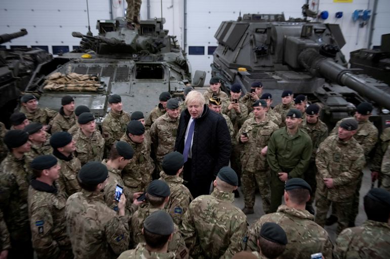 UK prime minister Boris Johnson surrounded by British soldiers in fatigues with tanks in the background at the Tapa military base in Estonia