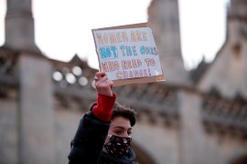 A woman holds a sign saying 'women are not the ones who need to change' during a vigil for Sarah Everard in Cambridge, Britain