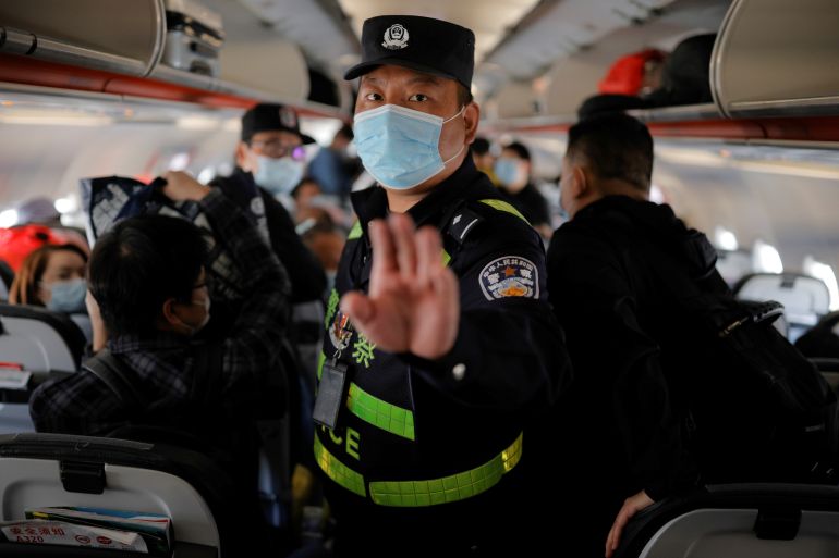 A uniformed police officer in China stands in the central aisle and orders journalists from Reuters news agency to get off a busy flight