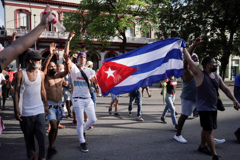 A group of protesters carrying a Cuban flag