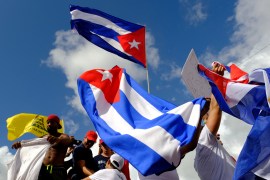 Protesters waving three Cuban flags