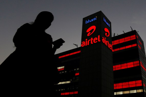 A girl checks her mobile phone as she walks past the Bharti Airtel office