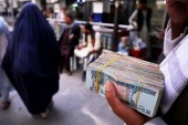 A person holds a bundle of afghani banknotes at a money exchange market, following banks and markets reopening after the Taliban took over in Kabul, Afghanistan on September 4, 2021 [File: Reuters/Stringer]