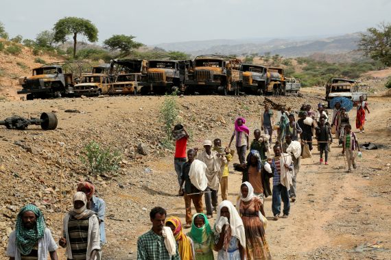 Villagers return from a market to Yechila town in southcentral Tigray walking past many burned vehicles
