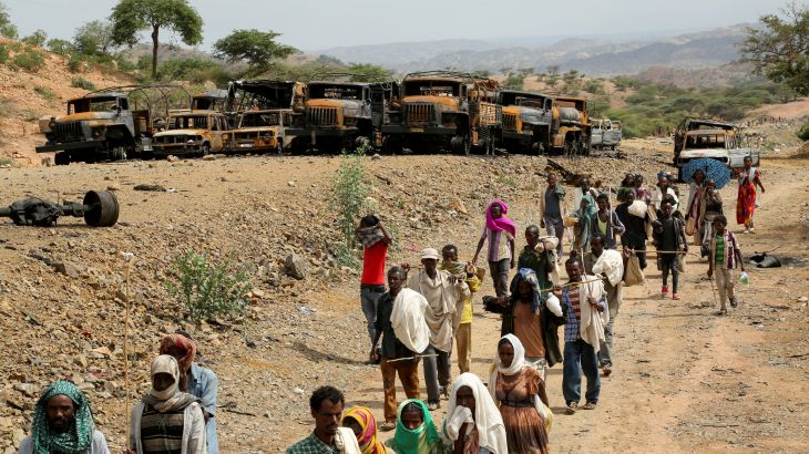 Villagers return from a market to Yechila town in southcentral Tigray walking past many burned vehicles