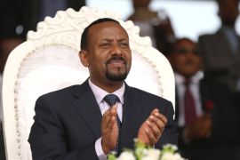 Ethiopia's prime minister Abiy Ahmed sits on a chair and claps during a rally