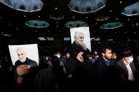 Iranian men hold up pictures of Qassem Soleimani