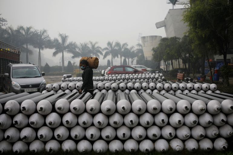 A labourer walks past the empty oxygen cylinders outside a COVID-19 care centre at an indoor sports complex in New Delhi, India, January 5, 2022