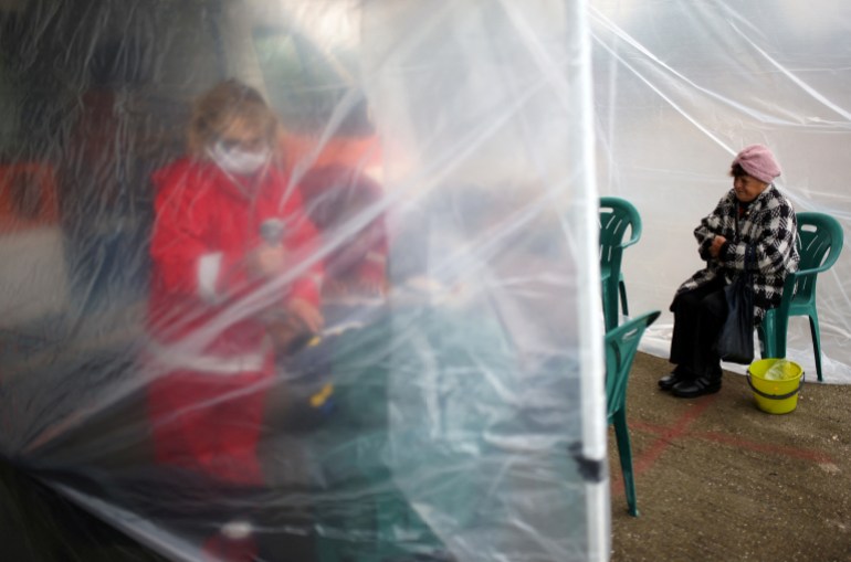 A woman awaits to receive a dose of vaccine against the coronavirus disease by a medical personnel from a mobile unit in the village of Krushovitsa, Bulgaria