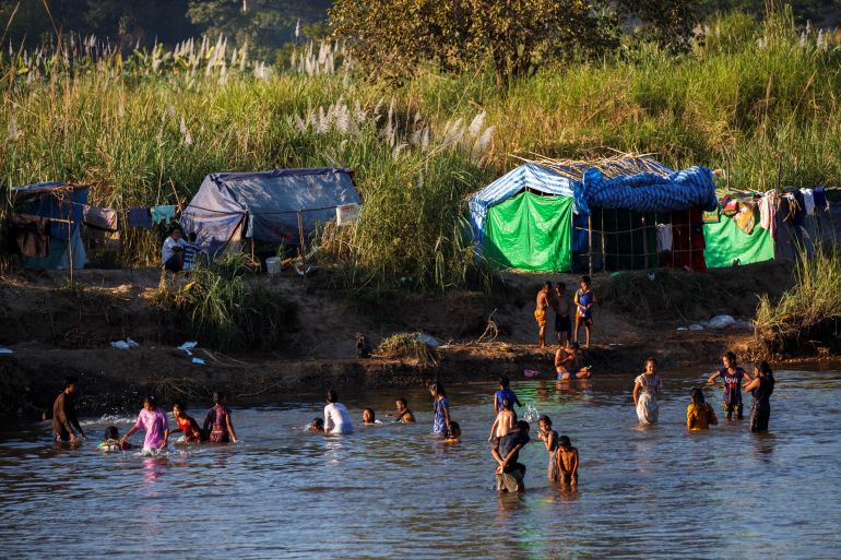 Refugees in the water of the Moei River close to their makeshift encampment in Myanmar.