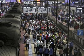 Commuters wait to board trains during evening rush hour at a railway station in Mumbai