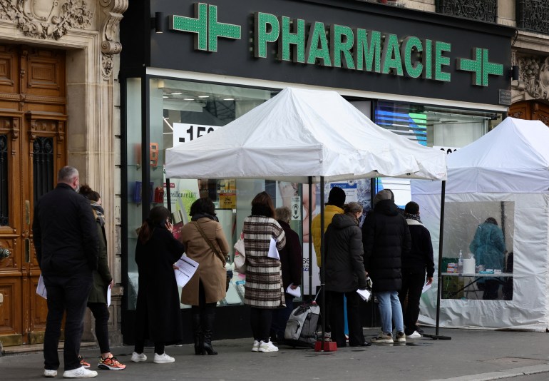 People queue for COVID-19 tests in front of a testing booth outside a pharmacy in Paris amid the spread of the coronavirus disease