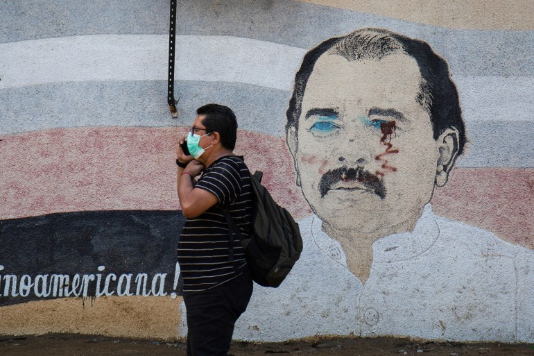 Man walking past mural of Nicaraguan president Daniel Ortega