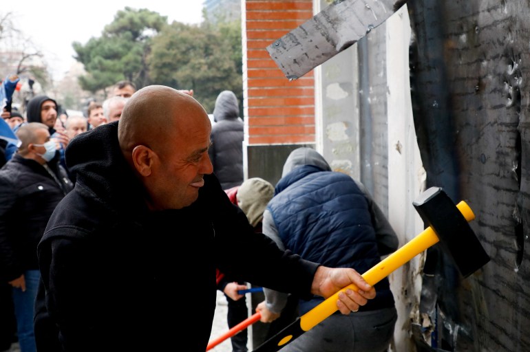 A protester attacks the Democratic Party headquarters in Tirana