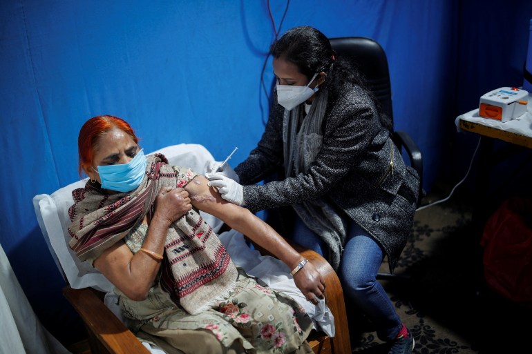 A woman receives a booster at a vaccination centre in New Delhi, India