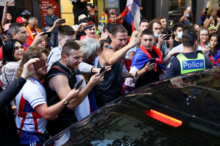 Supporters of Serbian tennis player Novak Djokovic gather around a car outside what is believed to be the location of his lawyer's office during an ongoing day of legal proceedings over the cancellation of his visa to play in the Australian Open, in Melbourne, Australia,