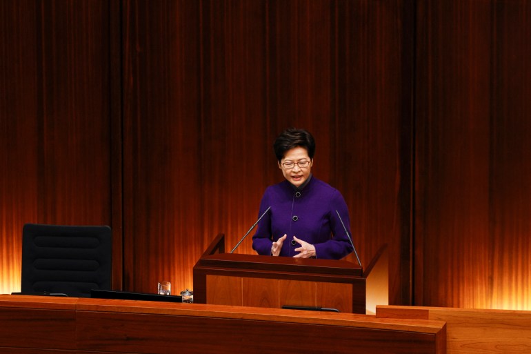 Carrie Lam in a royal blue outfit speaks to the assembled members of Hong Kong's 'patriots only' legislature