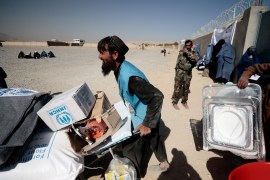 A UNHRC worker pushes a wheelbarrow with aid supplies outside Kabul