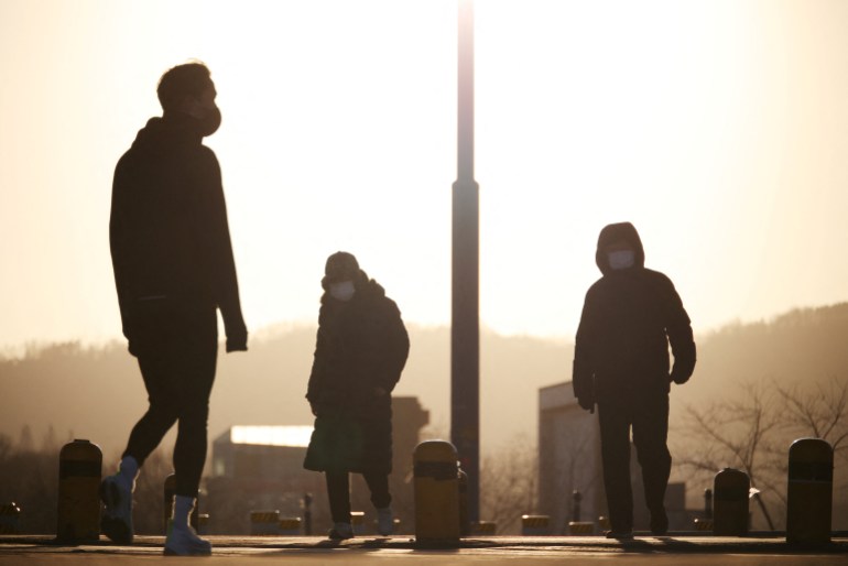 Three people wearing masks silhouetted against the sky on a cold morning in Seoul