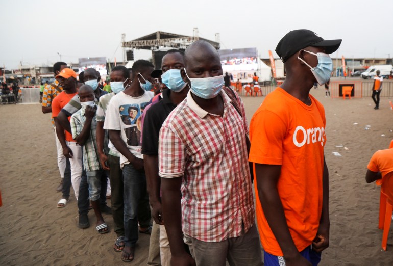 Ivory Coast fans wearing protective masks stand in line as they arrive to watch the Africa Cup of Nations soccer match between Equatorial Guinea and Ivory Coast on a big screen in Abidjan