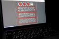 A laptop screen displays a warning message in Ukrainian, Russian and Polish, that appeared on the official website of the Ukrainian Foreign Ministry after a massive cyberattack,