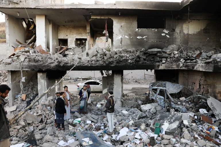 Guards stand on the rubble of a house hit by Saudi-led air strikes in Sanaa, Yemen