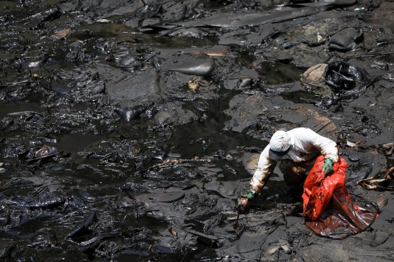 A worker cleans up an oil spill caused by abnormal waves in Ventanilla, Peru