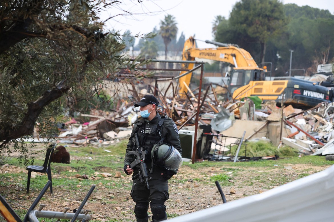 A member of the Israeli border police stands guard at the site of a demolished house in the Sheikh Jarrah