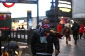 A man wearing a protective face mask walks through Piccadilly Circus, London [File: Henry Nicholls/London]