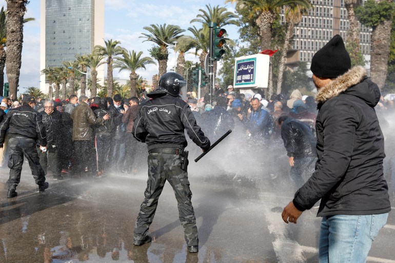 Demonstrators are hit by a water cannon during a protest against Tunisian President Kais Saied's seizure of governing powers, in Tunis