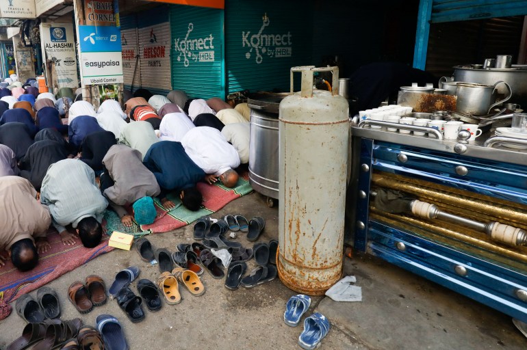 People pray on Friday in front of a market in Karachi