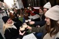 A group of women enjoy their beer while sitting at a table at a restaurant or bar outside in December