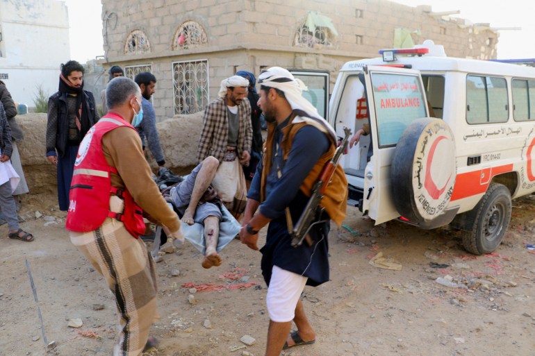 Two rescuers carry an injured man to a waiting ambulance after the attack on the detention facility in Saada