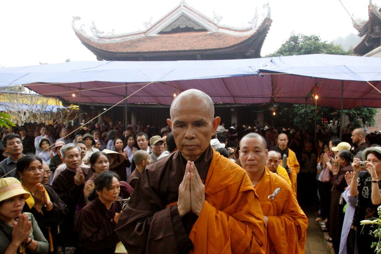 Buddhist monk Thich Nhat Hanh with his palms pressed together and wearing saffron robes, leads a mass at a temple near Hanoi in 2001. He has died at the age of 95