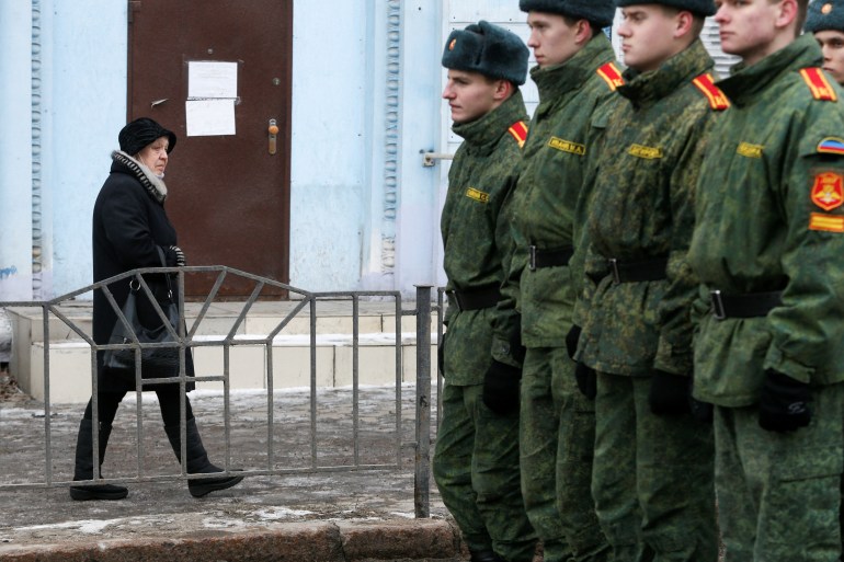 A woman walks past cadets of the self-proclaimed Donetsk People's Republic