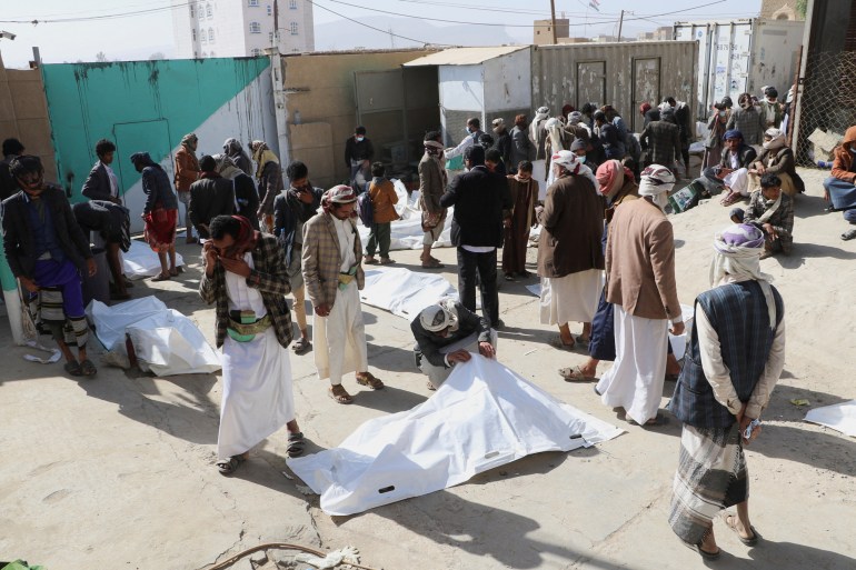 Relatives of victims inspect bodies of people killed by air strikes in Saada, Yemen