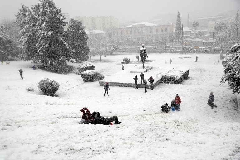 الشباب يلعبون في الثلج أثناء تساقط الثلوج بغزارة في أثينا ، اليونان