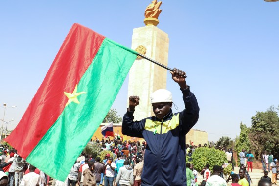 A man holds a national flag as people gather in support of a coup that deposed President Roch Kabore