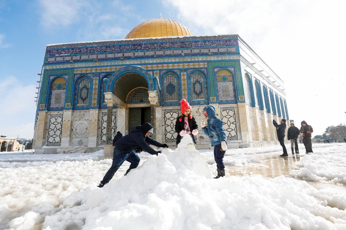 Children build a snowman in front of the Dome of the Rock,