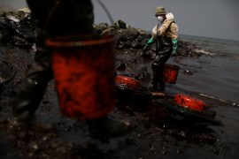 Workers clean up an oil spill on the Peruvian coast