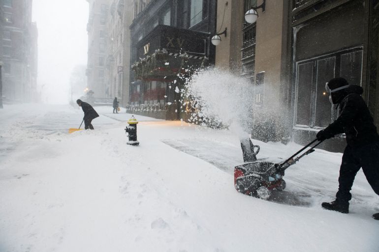 Employees of the XV Beacon Hotel clear snow during a Nor'easter storm in Boston