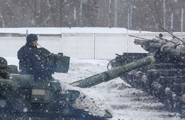 A service member drives a tank during snowfall as a mechanised brigade of the Ukrainian Armed Forces holds drills outside Kharkiv