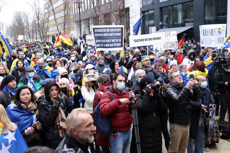 A crowd of protesters holding up signs and the national flag of Bosnia are seen outside in Brussels, Belgium