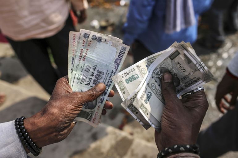 A man counts Indian rupee banknotes
