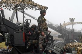 Indian soldiers stand next to guns on the India-China border in Arunachal Pradesh state