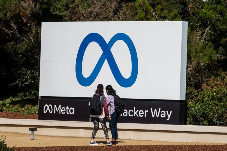 Visitors take photographs in front of signage at Meta Platforms headquarters in Menlo Park, California