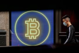 A commuter passes a digital display of cryptocurrency Bitcoin in Central district in Hong Kong.