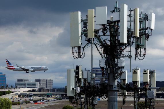 An American Airlines commercial aircraft flies past a cell phone tower as it approaches to land at John Wayne Airport in Santa Ana, California United States
